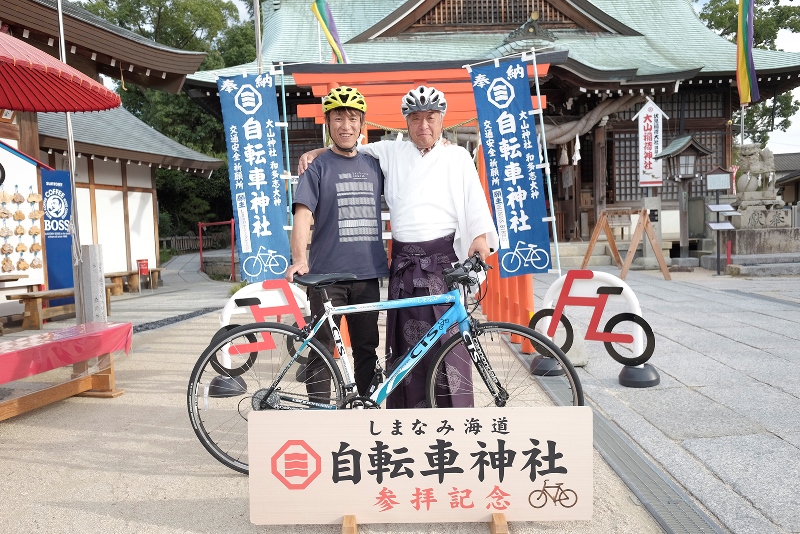 自転車神社・大山神社の宮司、巻幡俊さんと記念写真